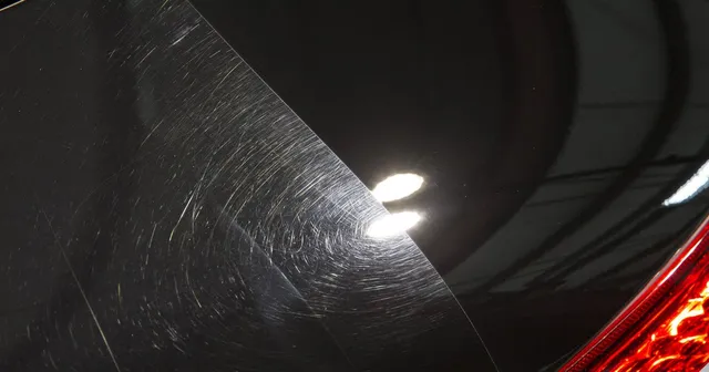 Close-up of black supercar paint showing swirl marks on the left and corrected glossy finish on the right after paint correction