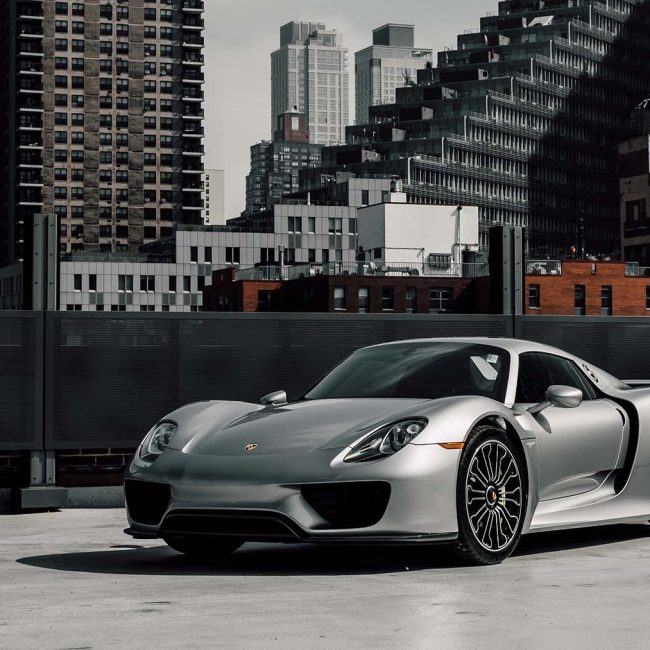 Silver Porsche 918 Spyder parked on rooftop with New York City skyline in the background, highlighting pristine paintwork ideal for full-body PPF